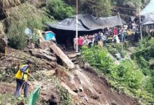 Uttarakhand Cloudburst Tragedy: 9 Missing, Char Dham Yatra Halted 8 Rescue worker clearing debris after Uttarakhand Cloudburst, with people watching from a safe distance near damaged tents.