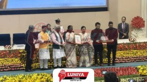 राष्ट्रपति द्रौपदी मुर्मु मीरा-भायंदर अधिकारियों को स्वच्छ भारत पुरस्कार भेंट करती हुईं। मंच पर मनोहर लाल खट्टर सहित कई मंत्री और गणमान्य व्यक्ति मौजूद हैं। पृष्ठभूमि में रंग-बिरंगे फूलों की सजावट।